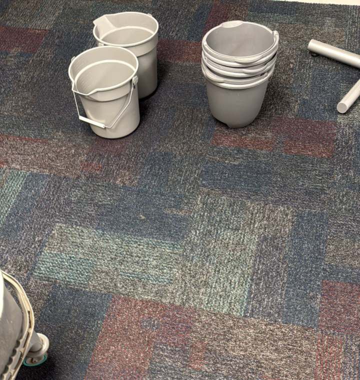 Catch buckets set out on commercial carpet under a leak